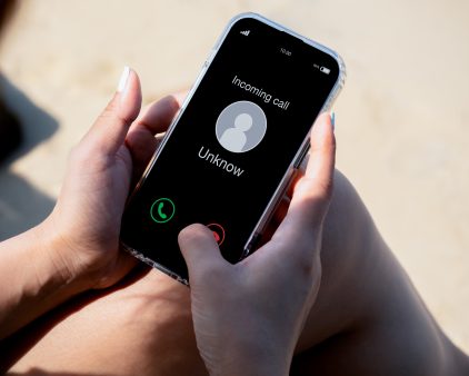 Incoming call with unknown caller, malicious phone calls concept. Unknown number displayed showing on smart mobile phone in woman hand on leave day at the beach. Spam and robocalls, scam call alert.